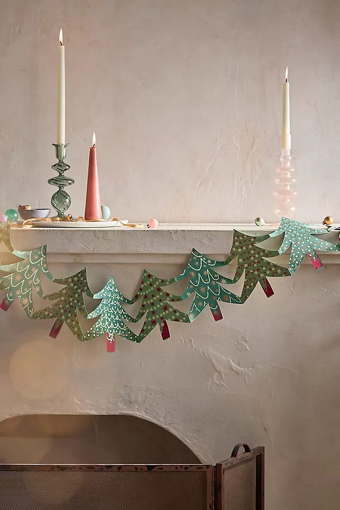 a fireplace mantle decorated with paper trees and candles