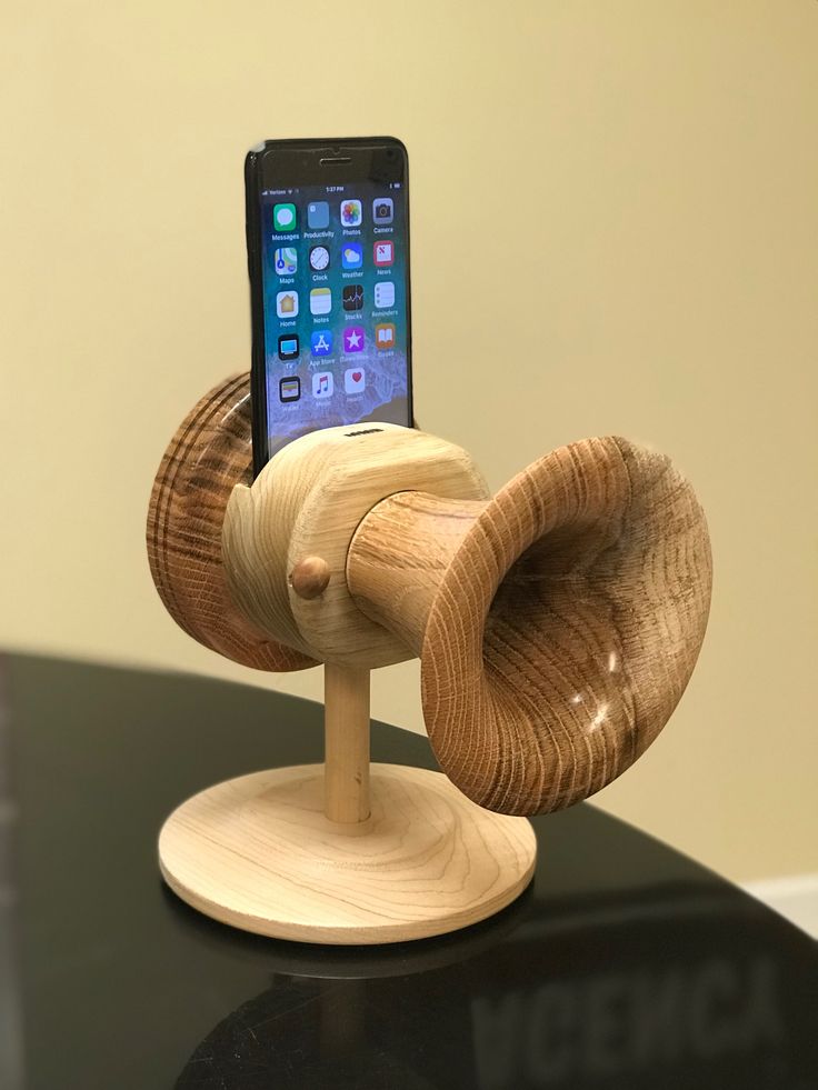 a cell phone holder made out of wood on top of a black table with an iphone in it