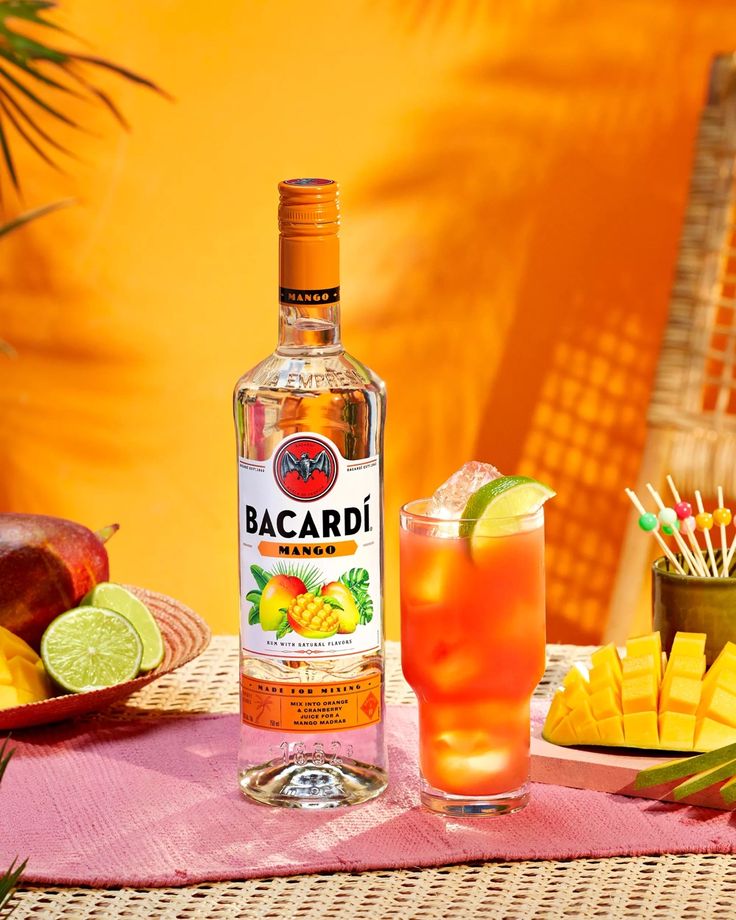 a bottle of bacardi next to a glass and plate with fruit