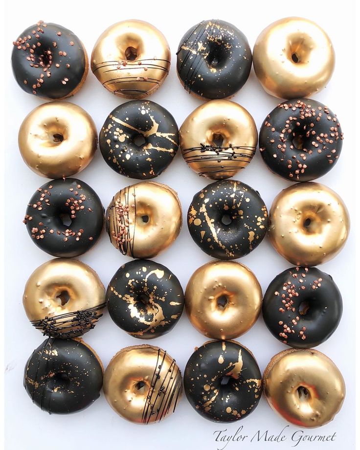 there are many donuts that have gold sprinkles on them and black frosting