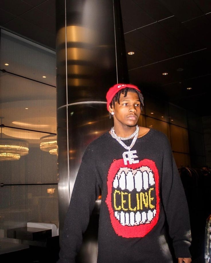 a young man wearing a sweater with the word celine printed on it, standing in front of an elevator