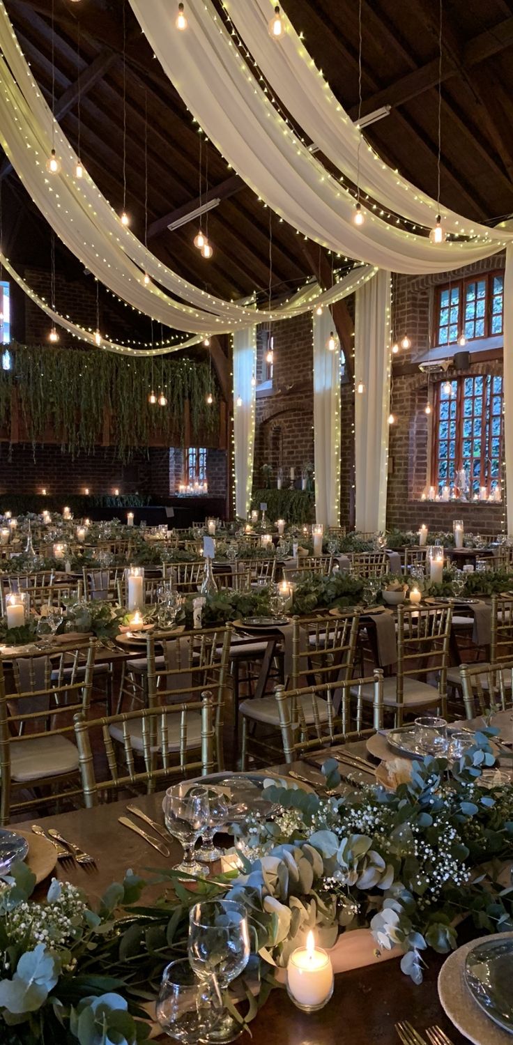 the tables are set with candles and greenery for an elegant wedding reception at this venue