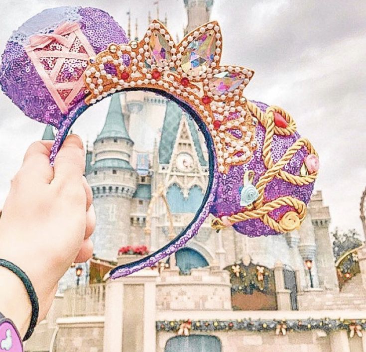 a hand holding a mirror in front of a castle with a princess's head on it