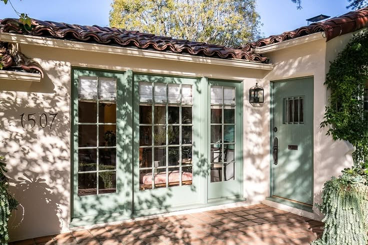 a house with green doors and tiled roof