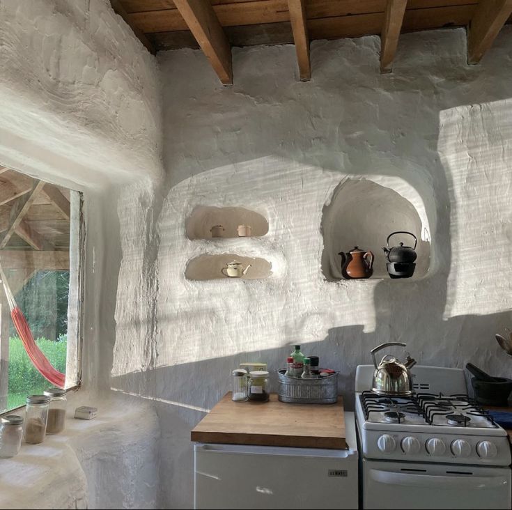 a stove top oven sitting inside of a kitchen next to a wall covered in stone