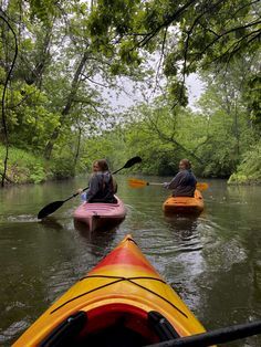 three people in kayaks paddling down a river