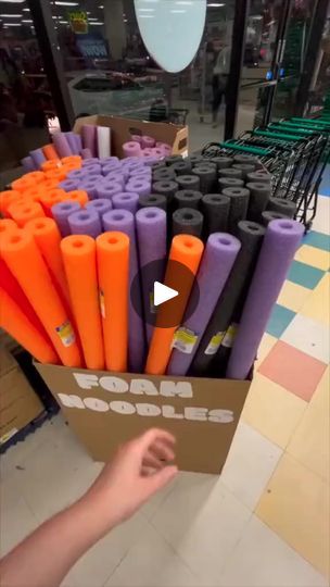 a cardboard box filled with orange and purple crepe sticks in a store aisle