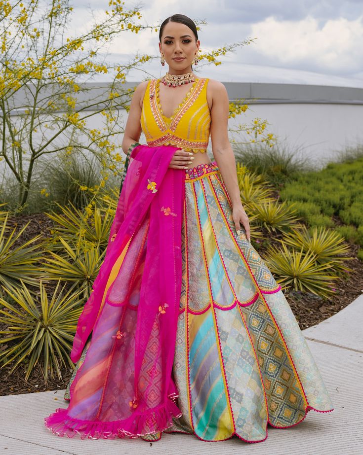 A multi-colored brocade mosaic scalloped lehenga paired with a yellow silk blouse and a pink tulle dupattaFrom Liz Paul’s Signature collection DELIVERY TIMEPlease allow 8-12 weeks for your outfit to arrive. FABRIC DETAILSRaw silk. Professional cleaning only. Fusion Style Multicolor Sets For Navratri, Multicolor Fusion Sets For Navratri, Multicolor Navratri Sets, Multicolor Silk Anarkali Sharara, Fusion Style Festive Silk Lehenga, Fusion Style Multicolor Sets With Traditional Drape, Fusion Style Lehenga For Festivals, Fusion Style Designer Choli For Festivals, Fusion Style Multicolor Cutdana Sets