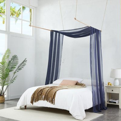 a bed with a blue canopy over it in a room next to a white wall