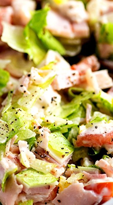 a salad with lettuce, tomatoes and meat on it is ready to be eaten