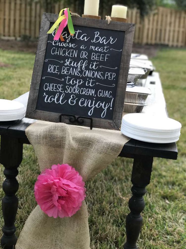 a chalkboard sign sitting on top of a wooden table next to a white plate