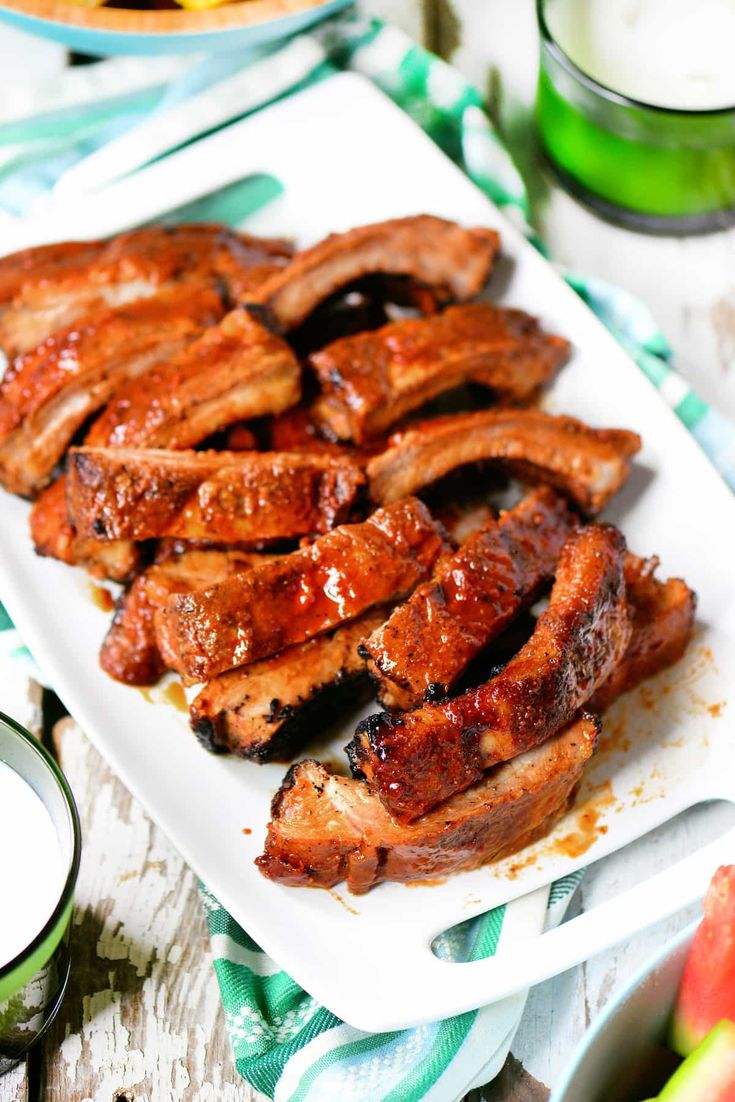 sliced meat on a white plate next to some fruit