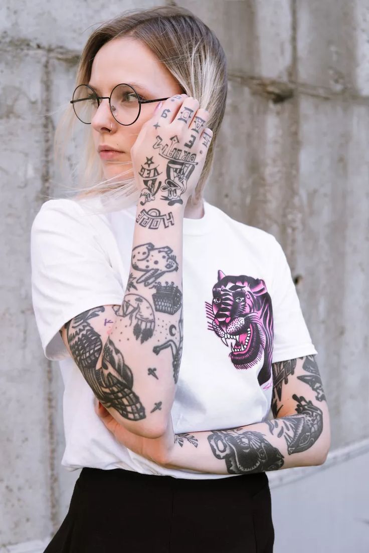 a woman with tattoos holding her hand up to her face