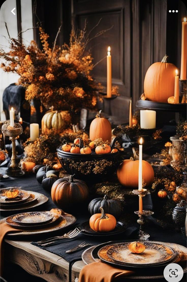 the table is set with pumpkins, candles and other decorations for halloween dinnerware