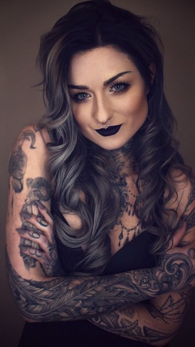 a woman with long hair and tattoos on her arms