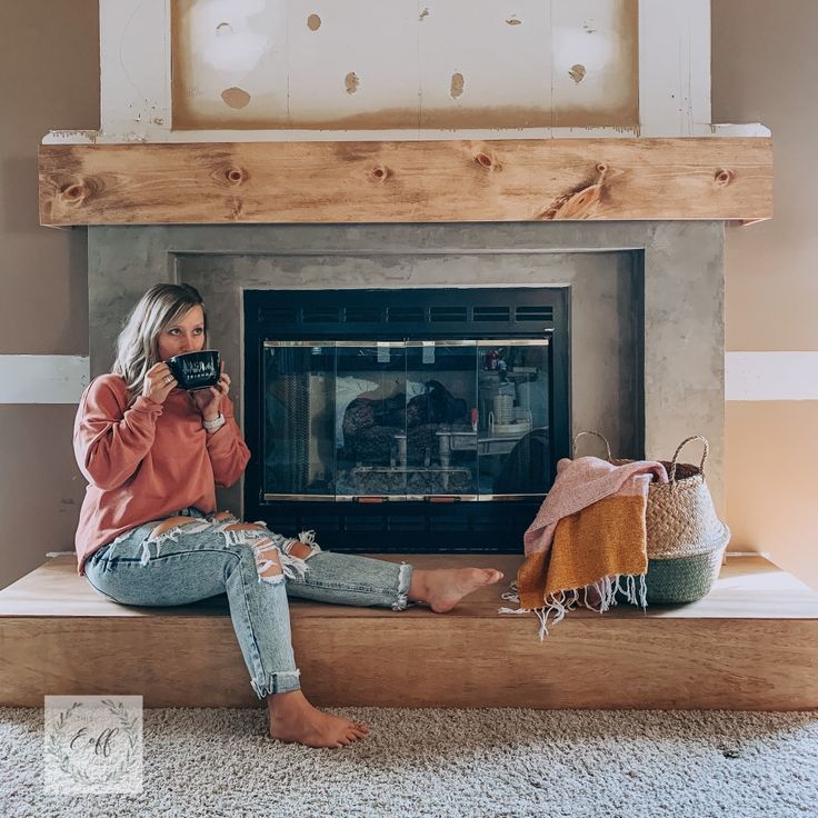 a woman sitting in front of a fireplace holding a camera