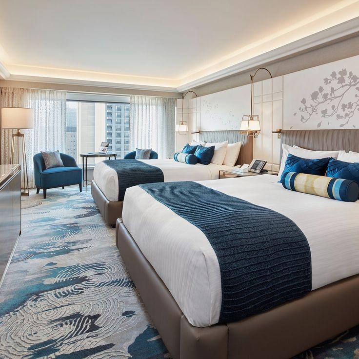 two beds in a hotel room with blue and white decor