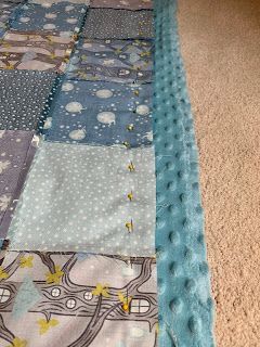 a close up of a patchwork quilt on the floor with blue and grey colors