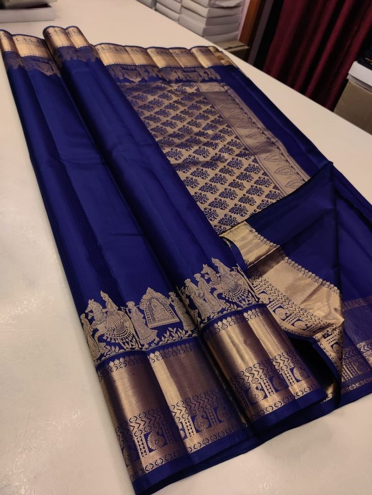 a blue and gold saree laying on top of a bed