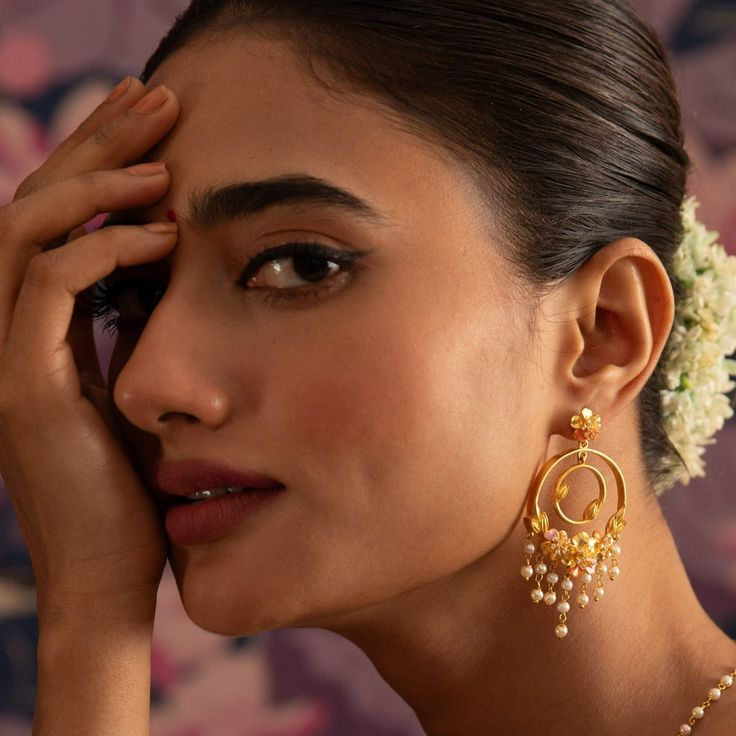 Description Tarinika’s Jalaja Collection celebrates the beauty and grace of flowers and pearls. The collection features exquisite gold-plated jewelry with floral designs, with soft enamel paint, and hand-woven pearl chains. This statement chandbali earring features two hoops. It adds a touch of glamour to any festive or wedding occasion. Details & Specifications: Materials used: Brass Alloy with Matte Gold & Enamel plating Weight – Earring-21.40 gm Length – Earring-7 cm Make it custom Want to m Meenakari 22k Gold Earrings, Traditional Gold Plated Danglers, Traditional Gold-plated Danglers, 22k Gold Wedding Danglers, Traditional Chandbali Earrings With Dangling Beads, Traditional Chandbali Jewelry With Dangling Beads, Temple Jewelry Chandbalis Drop Earrings, Gold-plated Chandbali Bridal Earrings, Gold Plated Chandbali Bridal Earrings