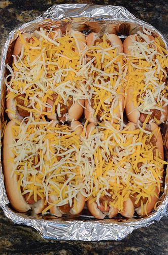 several hot dogs covered in cheese and sitting on tin foil