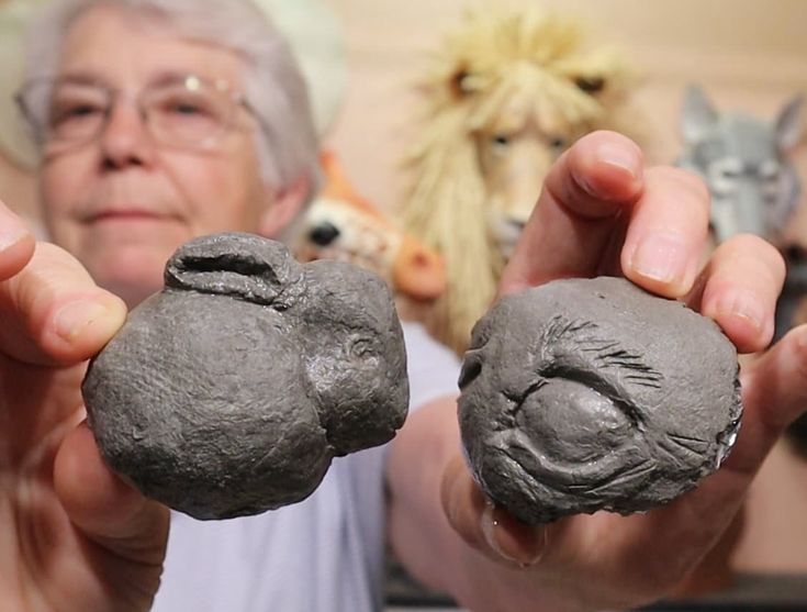 an older woman holding two clay animals in her hands