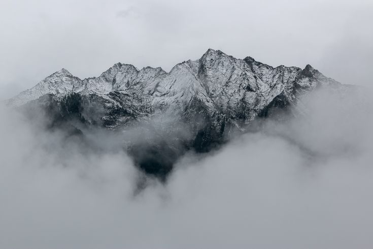 the mountains are covered in snow and clouds