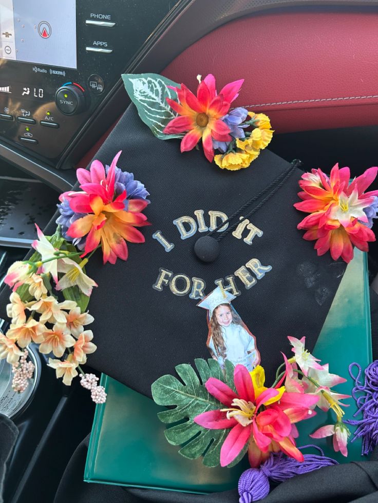 a graduation cap decorated with flowers and the words i did it for her