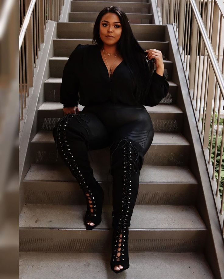 a woman sitting on some stairs with her legs crossed and wearing high heeled boots