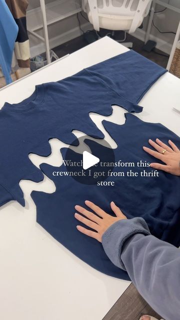 a person is making a t - shirt out of blue material with white letters on it