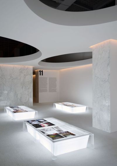 the interior of an art gallery with white marble walls and flooring, illuminated by recessed lighting