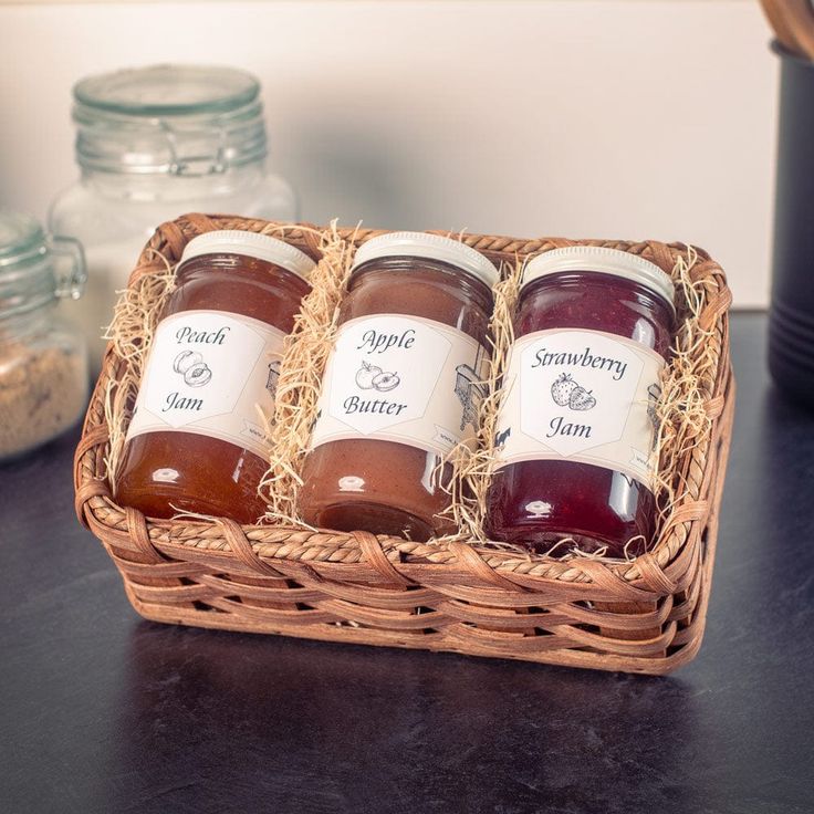 three jars of jam sit in a wicker basket