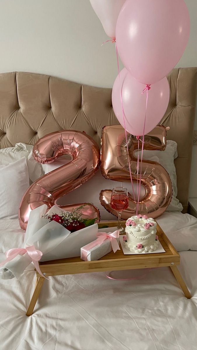 a birthday cake and balloons on a bed