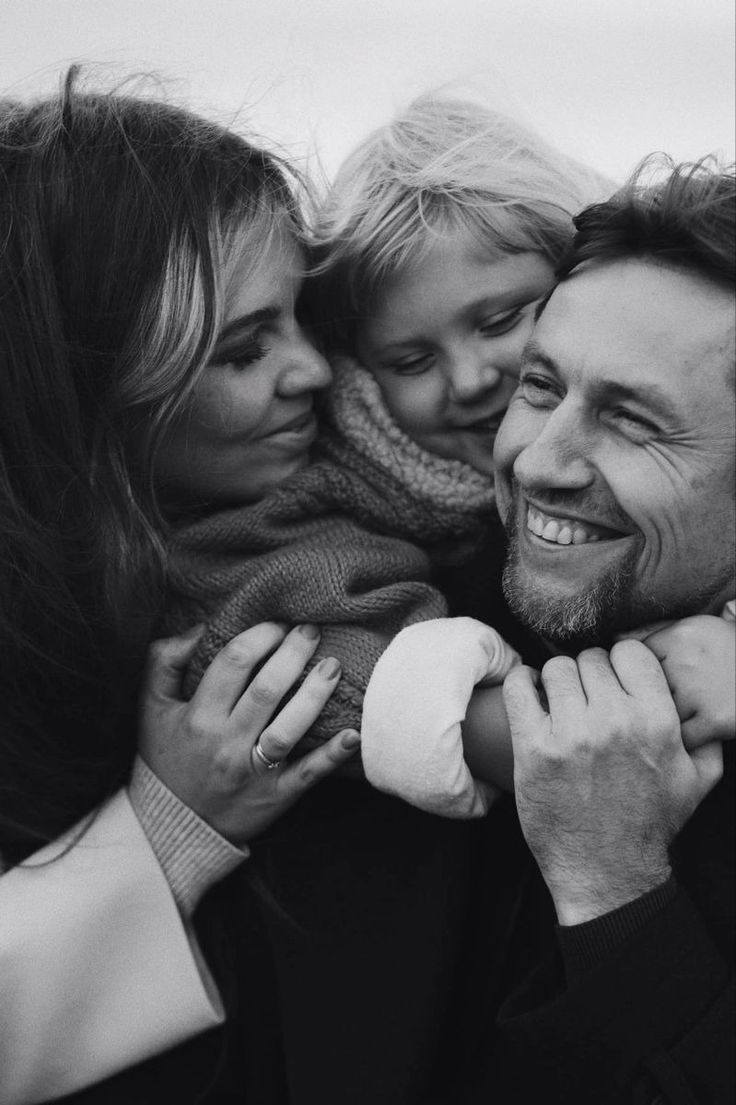 a black and white photo of a man, woman and child with their arms around each other