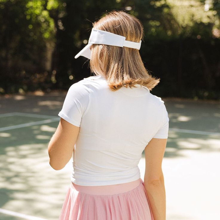 a woman standing on a tennis court holding a racquet in one hand and wearing a white headband