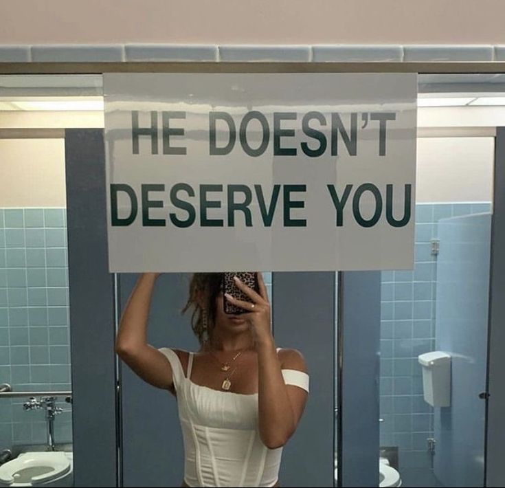 a woman holding a sign that says he doesn't deserve you in front of her