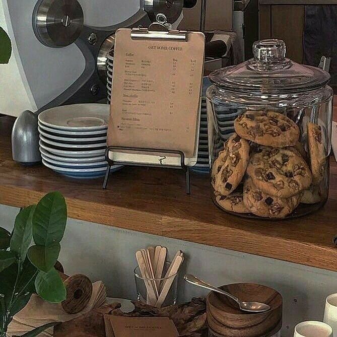 there are cookies in the glass jar on the shelf next to the coffee maker and other items