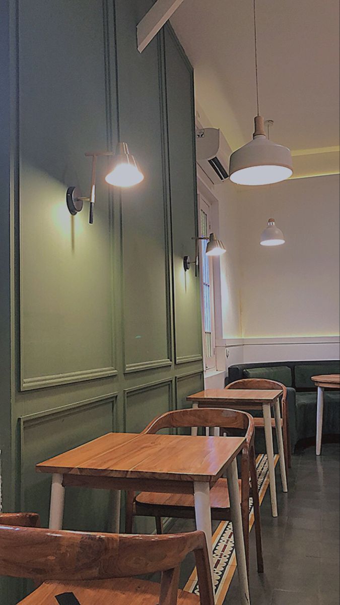 a row of wooden tables sitting next to each other in front of green wall mounted cabinets