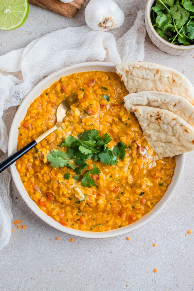 a white bowl filled with soup next to tortillas and cilantros