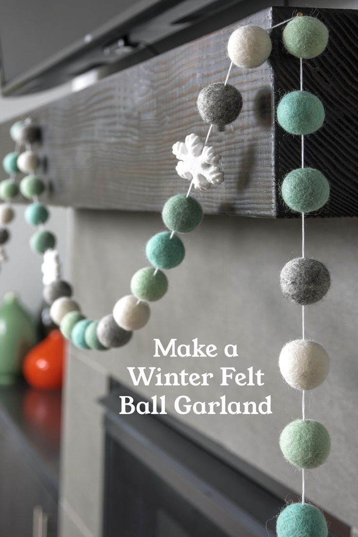 a garland made with felt balls hanging from the side of a fireplace