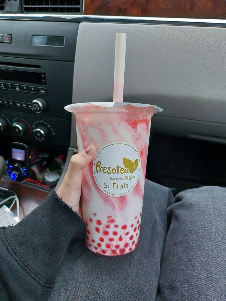 a person is holding up a drink in their hand while sitting in the backseat of a car