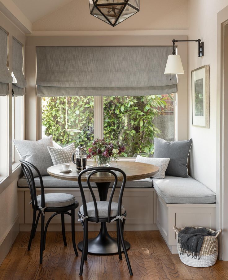 a table and chairs in front of a window with a bench next to the window