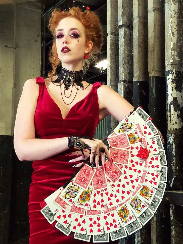 a woman in a red dress holding a deck of cards