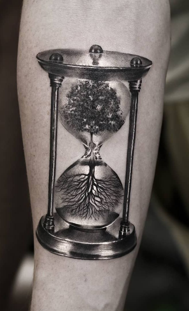 a man's leg with a tree in an hourglass tattoo on the calf