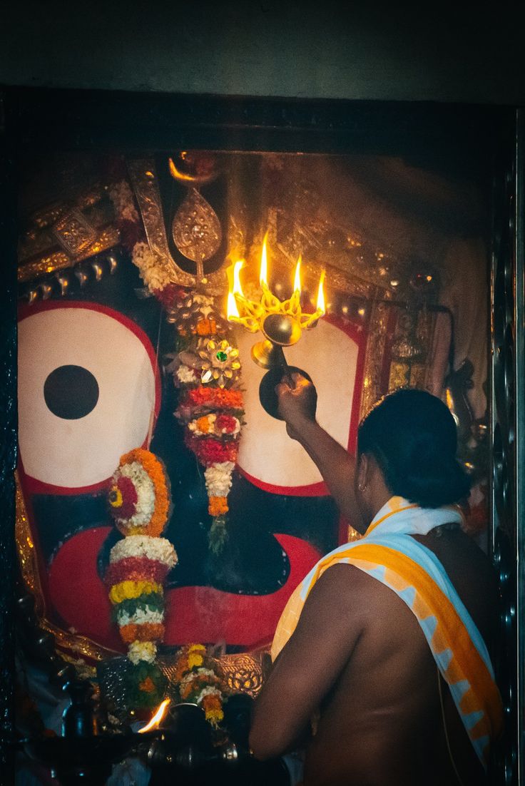 a man lighting candles on the face of a statue