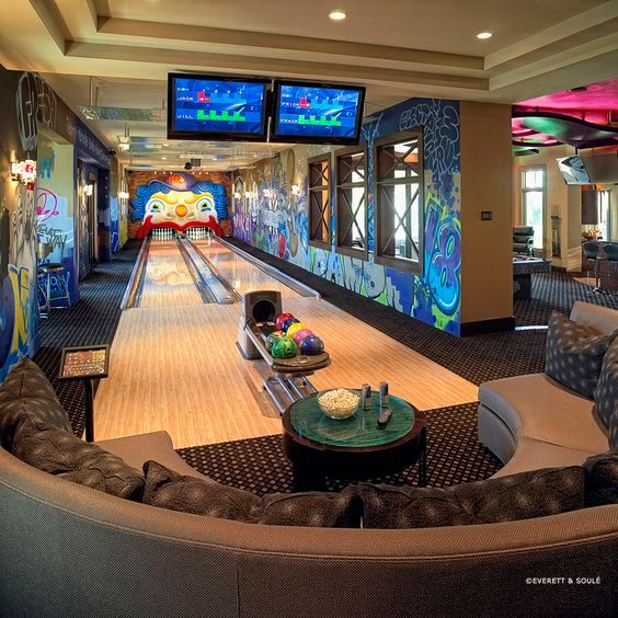 a bowling alley with couches, tables and televisions