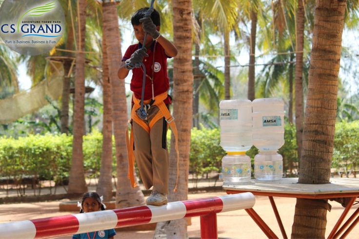 a man standing on top of a wooden table next to palm trees and water bottles