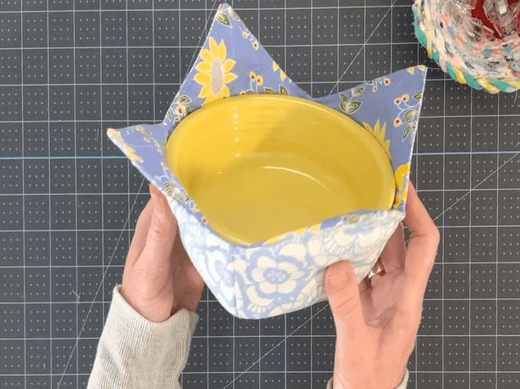 a person is holding a yellow bowl on top of a blue and white paper napkin