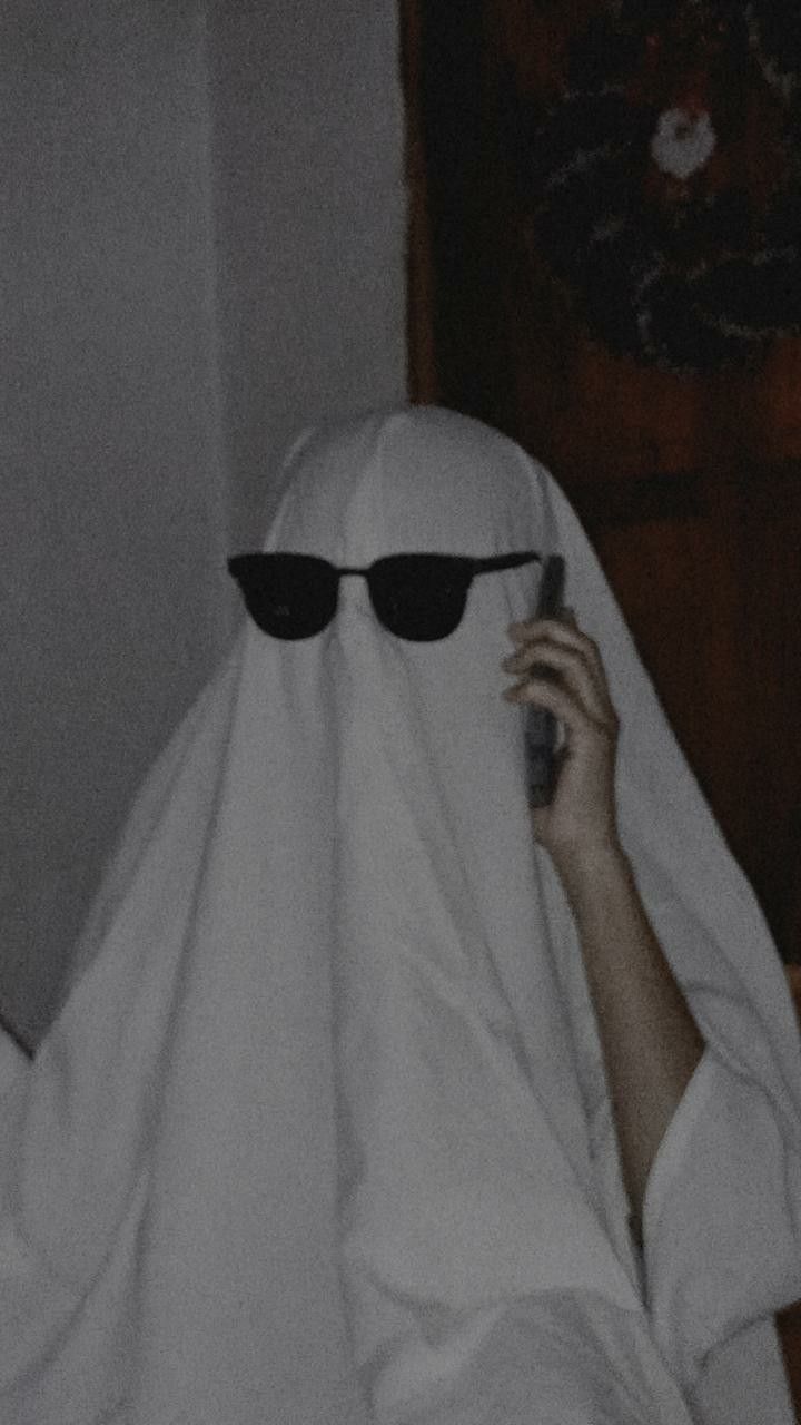 a person in a nun costume talking on a cell phone while wearing sunglasses and covering her head with a white cloth