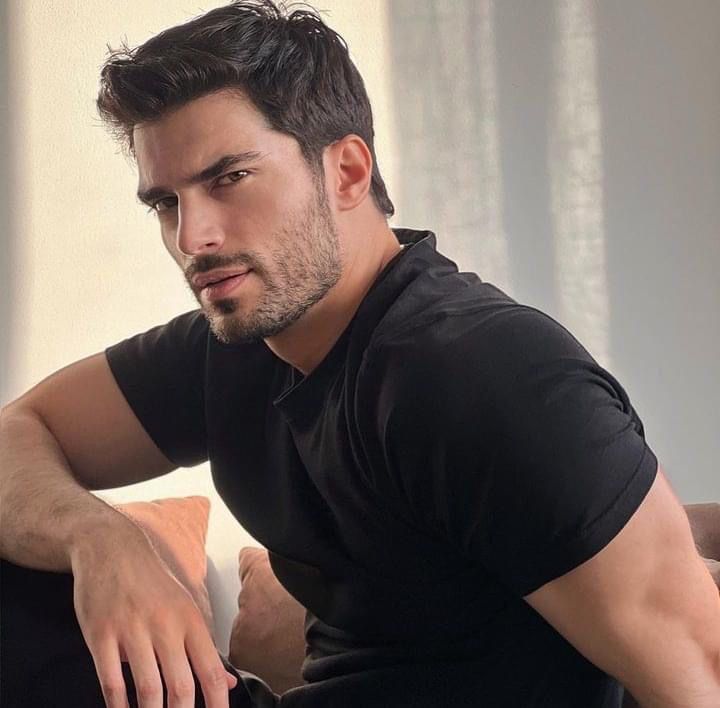 a man sitting on top of a couch wearing a black shirt